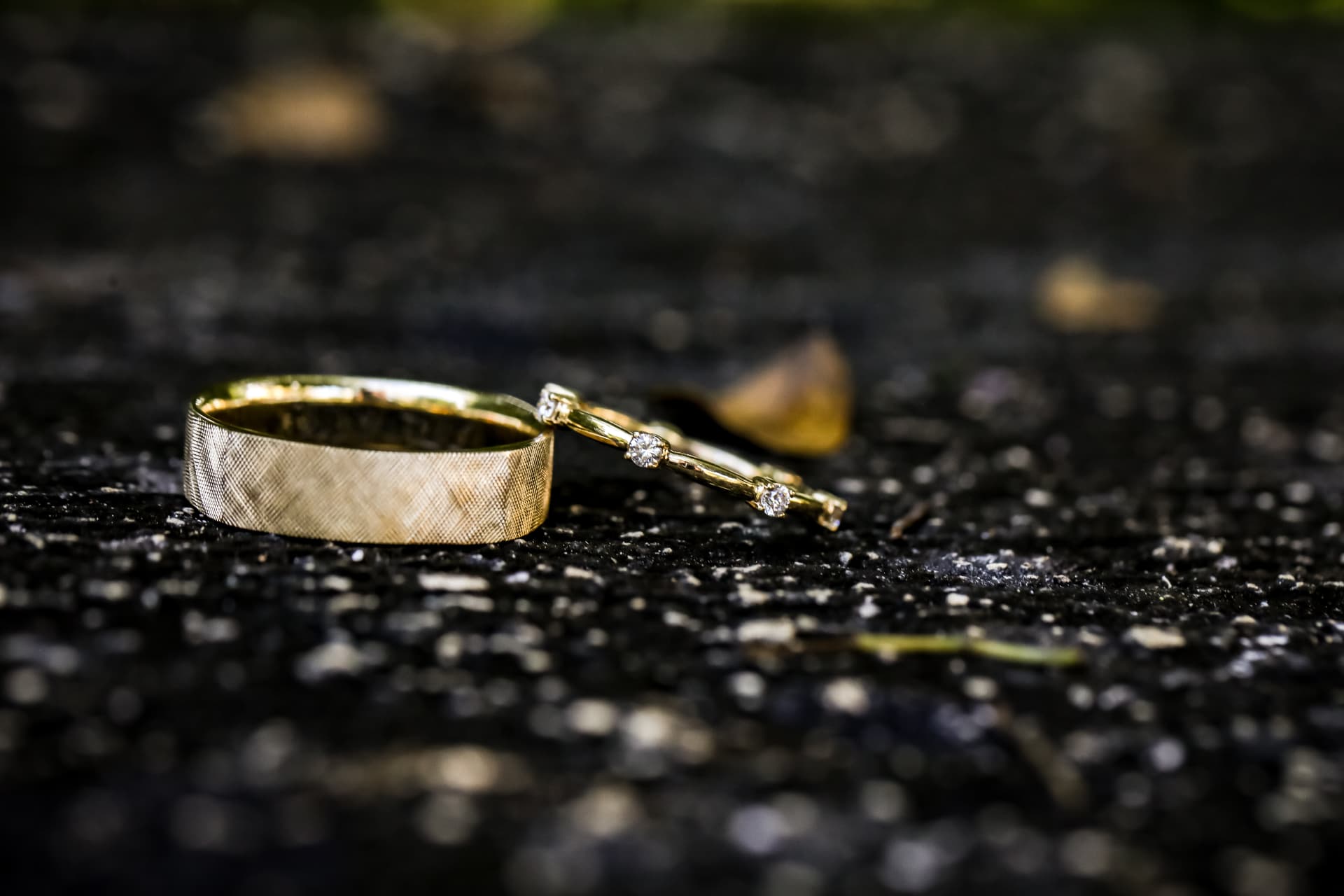 Argollas de boda doradas sobre una superficie oscura con reflejos naturales