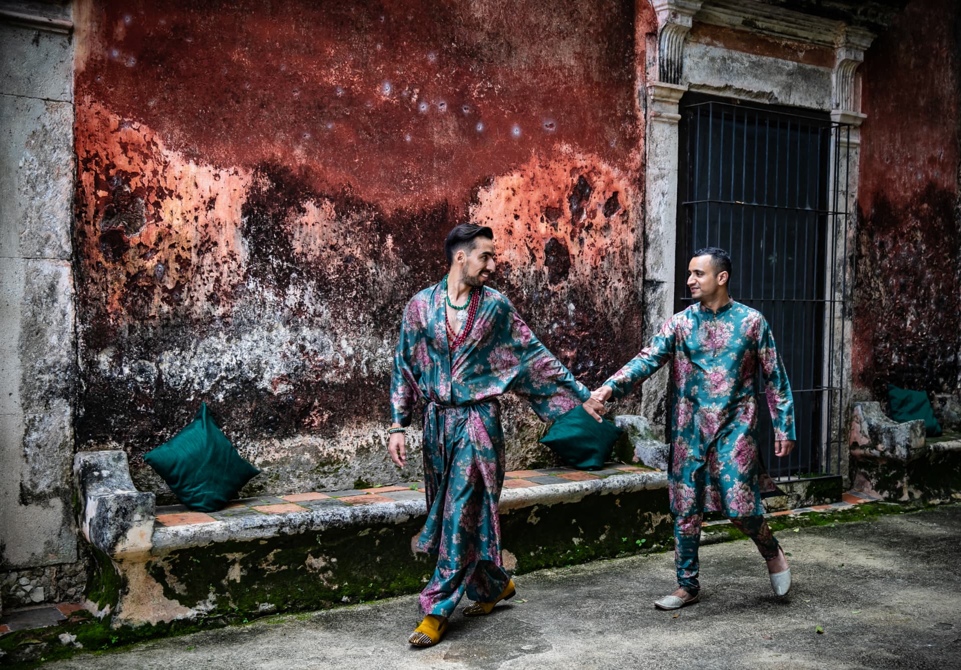 Dos novios con batas estampadas caminando de la mano durante los preparativos