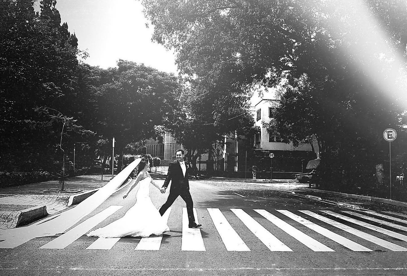 Novios cruzando la calle con velo al viento, sesión trash the dress