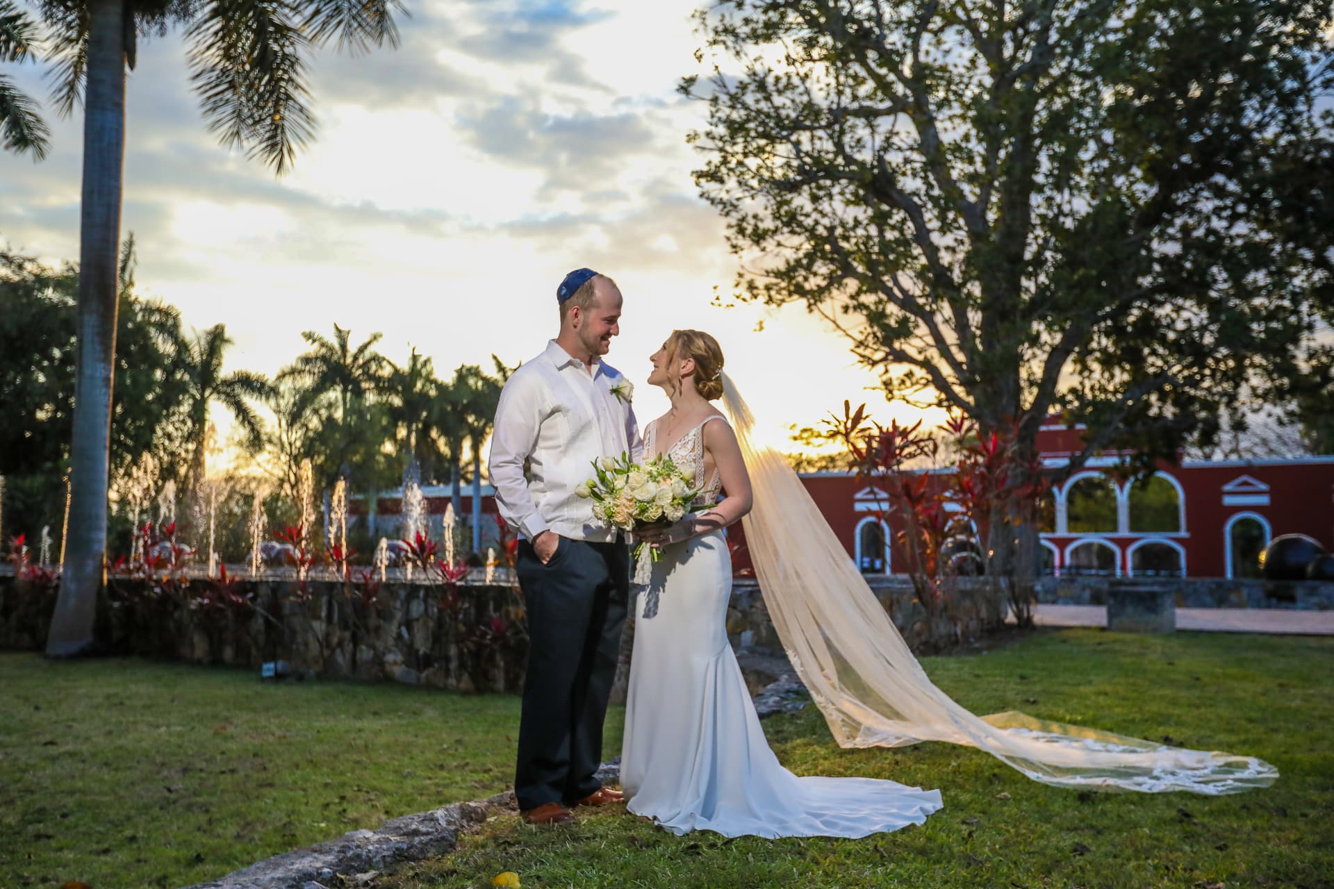 Pareja de novios en una hacienda al atardecer con el velo extendido