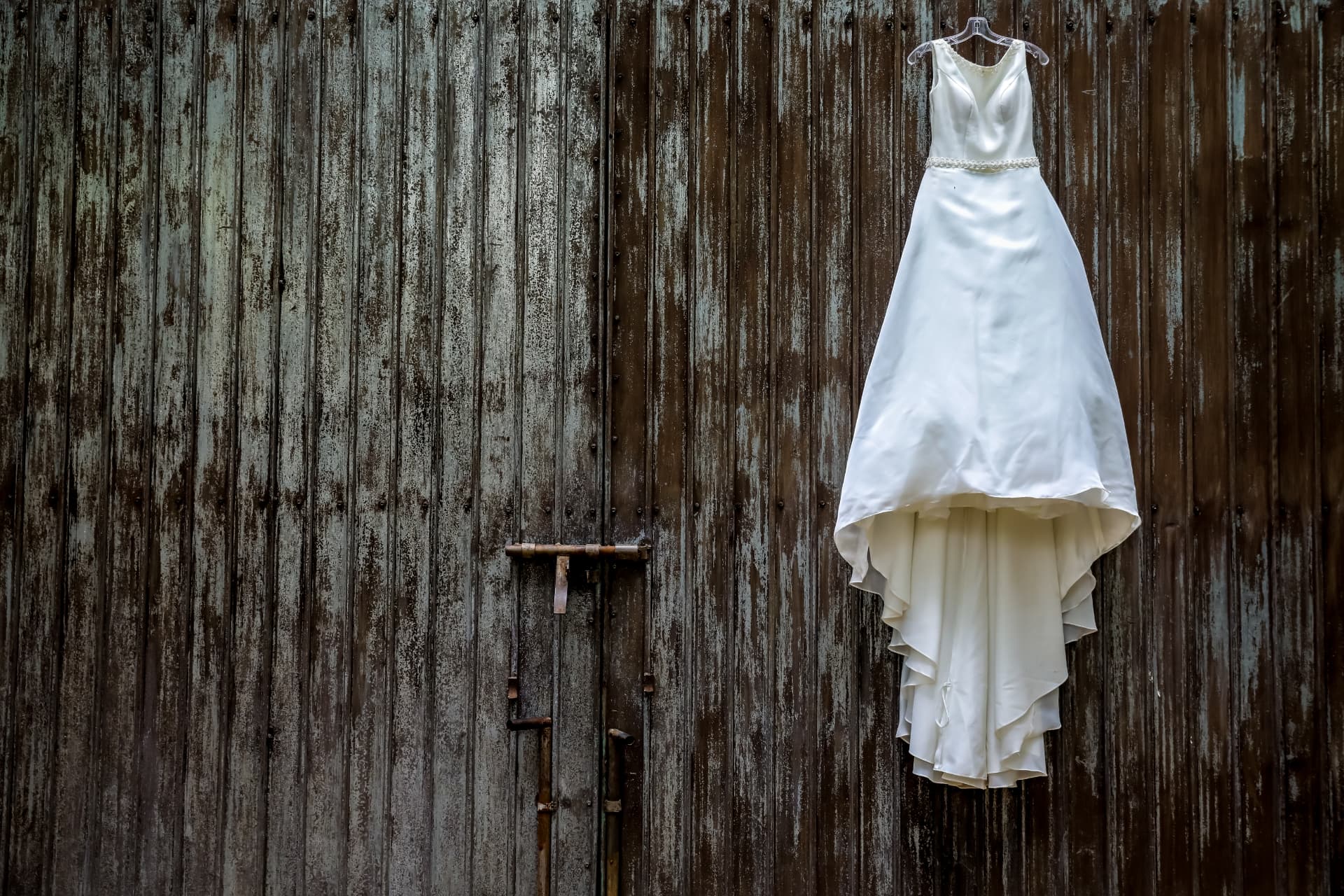 Vestido de novia colgado sobre una antigua puerta de madera