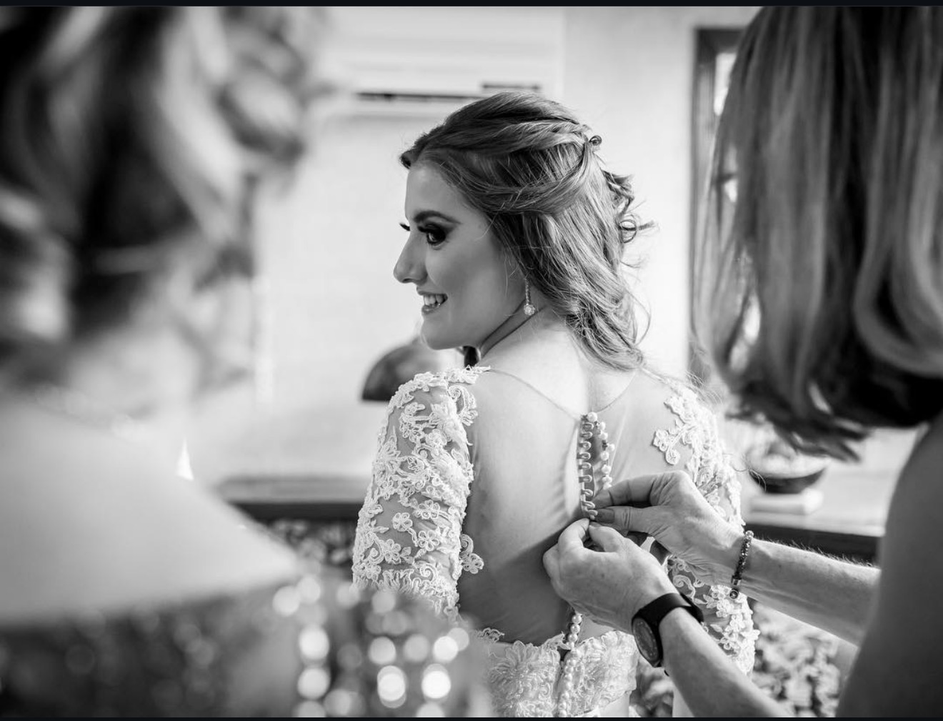 Novia abrochando su vestido de encaje, preparativos de boda