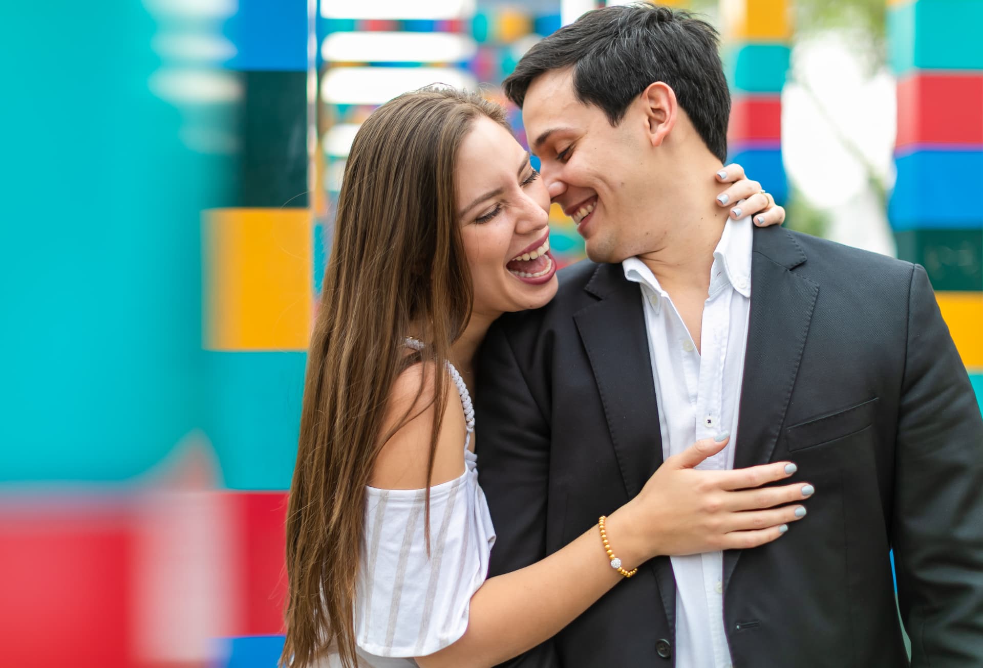 Pareja riendo frente a una instalación de colores, sesión save the date