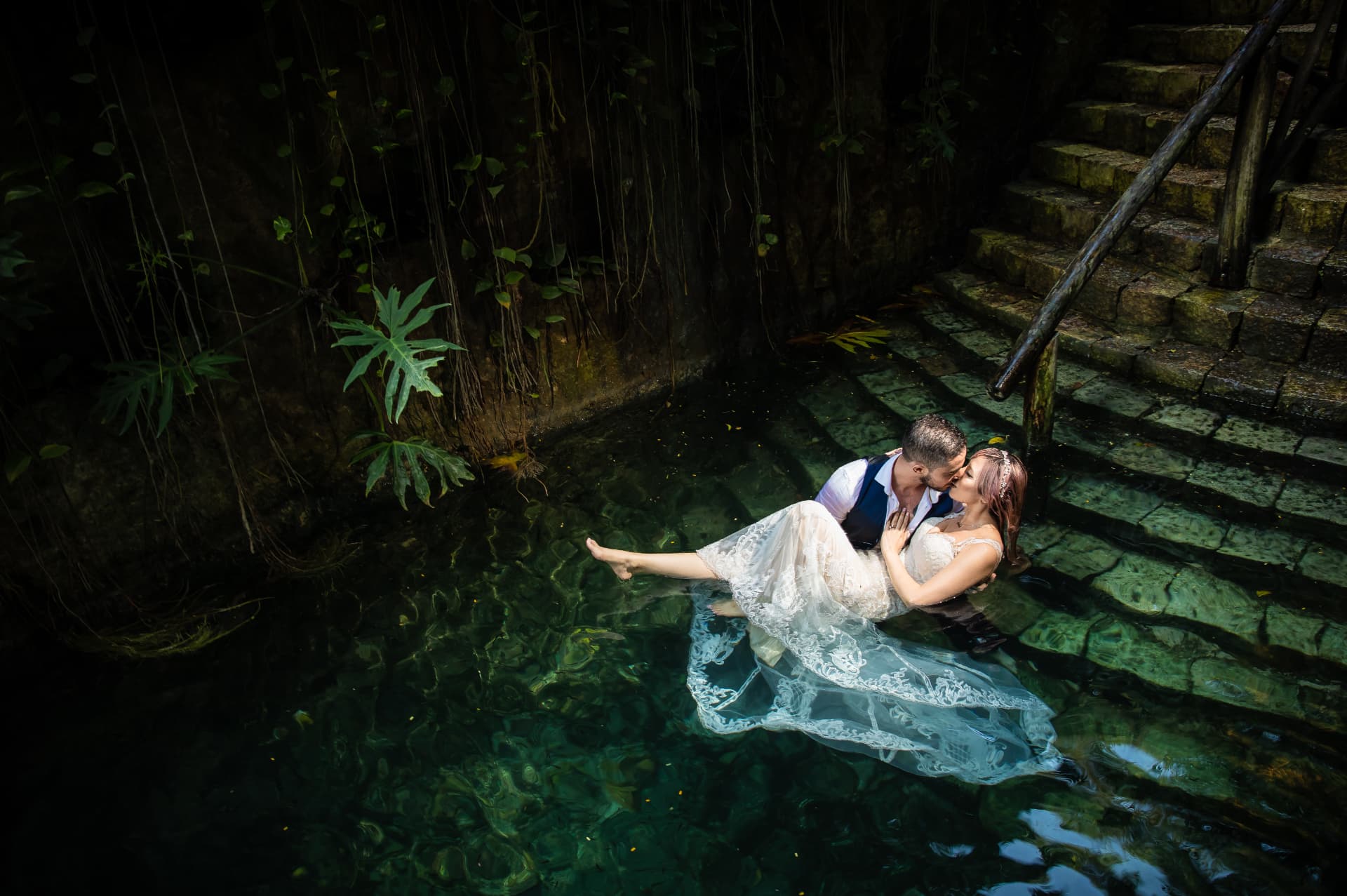 Novios en sesión trash the dress dentro de un cenote de aguas cristalinas