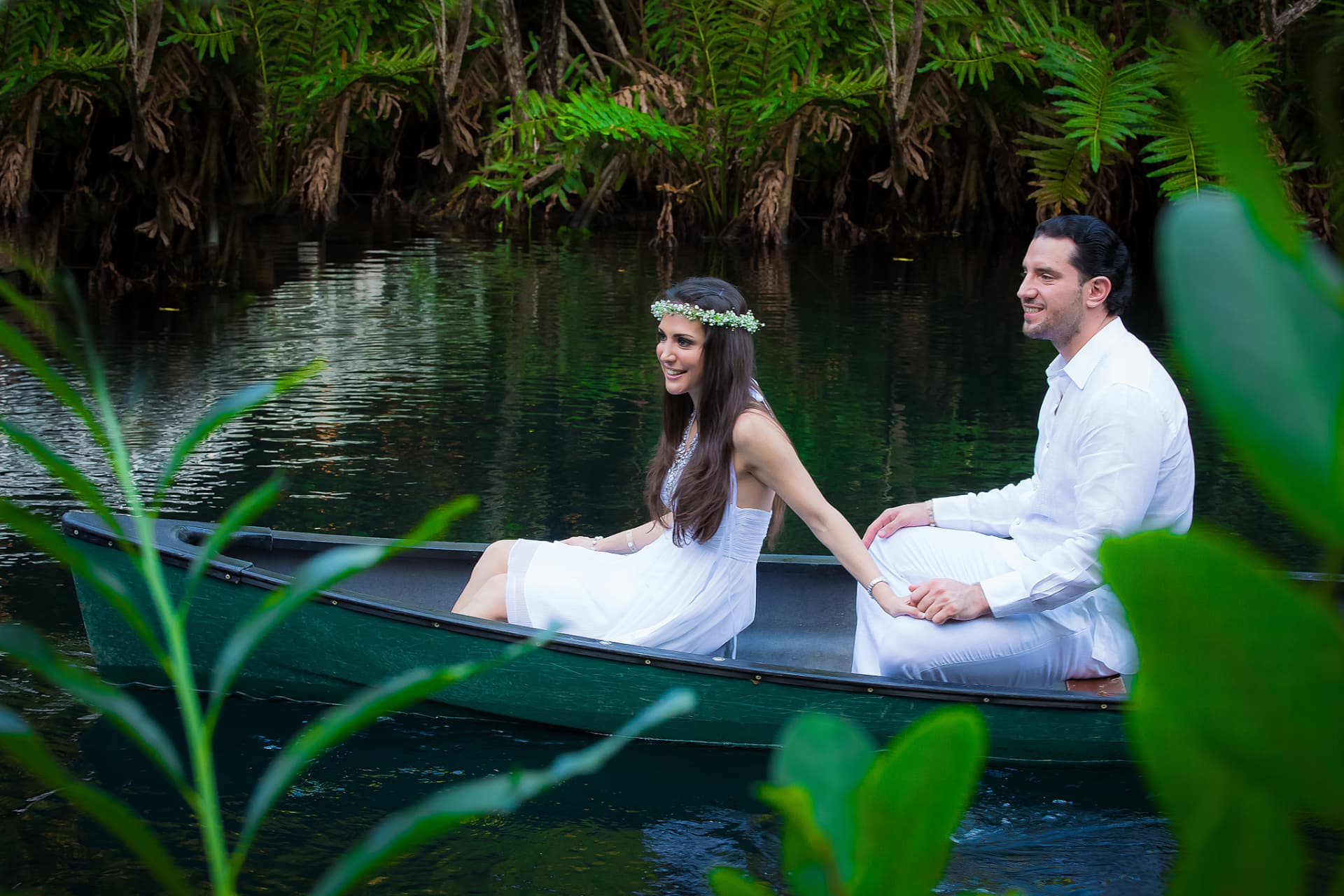Pareja vestida de blanco navegando en canoa entre vegetación tropical