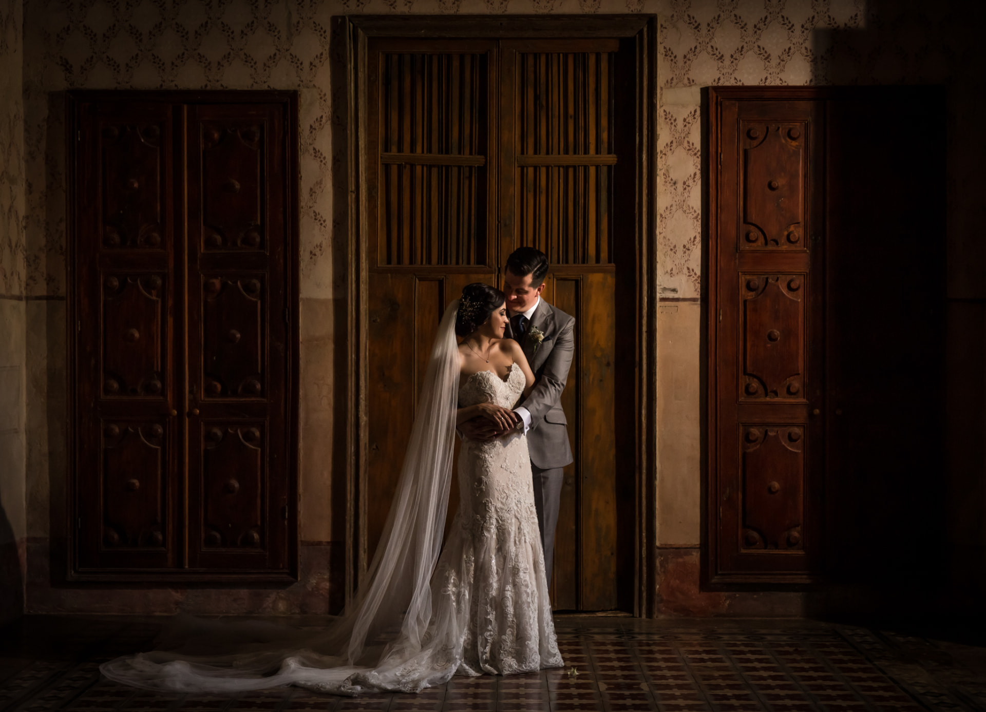 Novios en un retrato íntimo entre puertas de madera de una hacienda