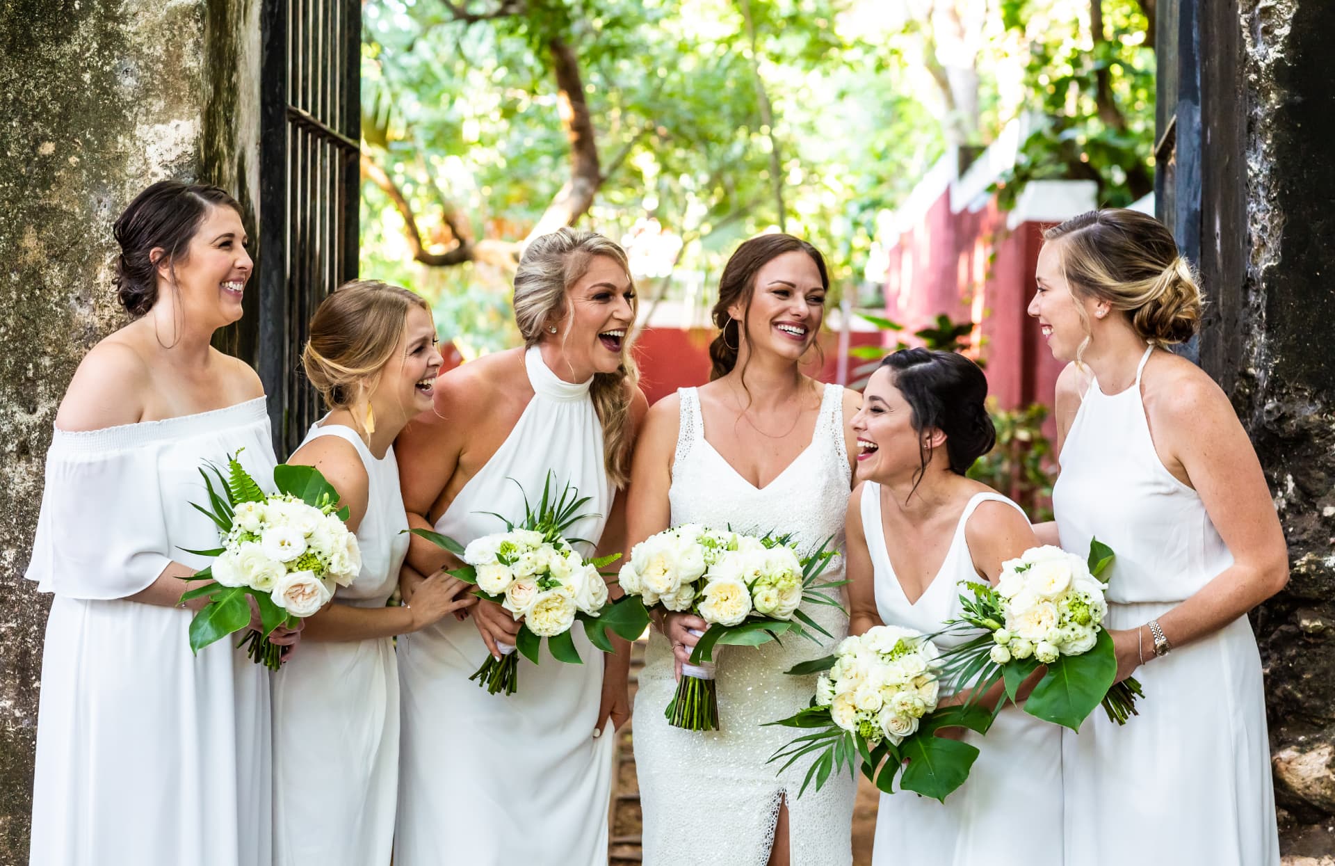Novia rodeada de sus damas de honor riendo juntas antes de la boda
